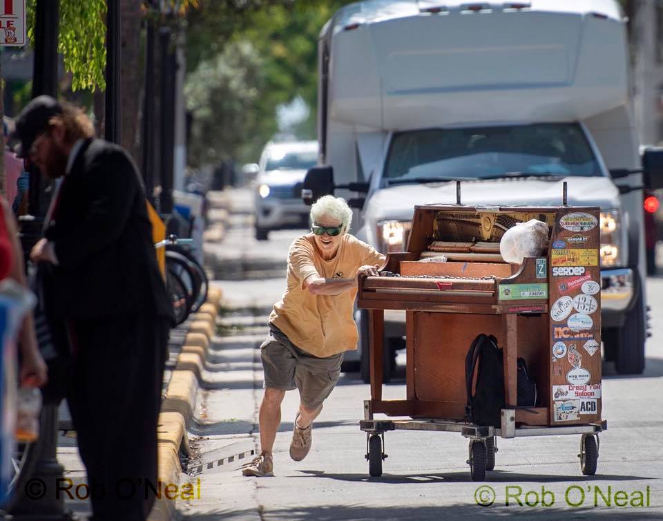 Barry Cuda pushing a piano on the street